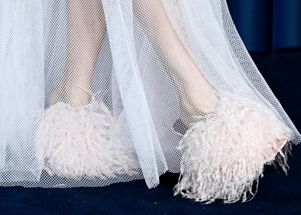 A detailed image of Sienna Miller’s Givenchy sandals with boudoir fringe, worn during her appearance at the 2025 Fashion Awards, complemented by a cutaway diamond net maxi dress.